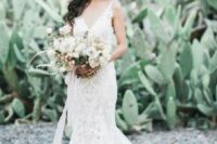 a fantastic lace mermaid wedding dress with thin straps and a V-neckline plus fresh flowers in her hair