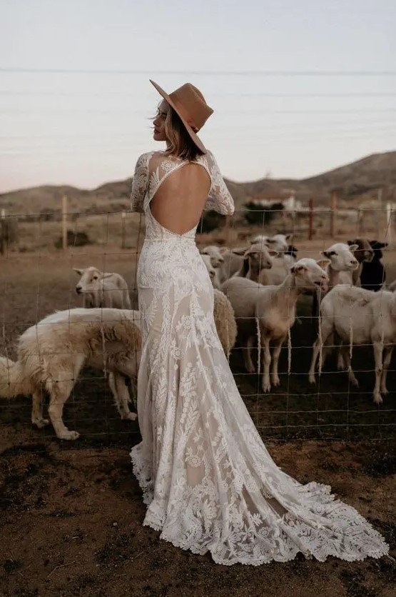 a lovely lace mermaid wedding dress with a keyhole back, long sleeves and a high neckline, a short train and a hat for a boho look