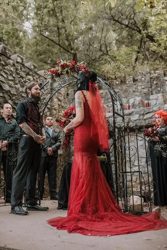 a red lace mermaid wedding dress with a train and an open back plus a red veil for a Gothic bride