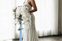 a sparkling mermaid wedding dress with straps, a deep neckline and a train, is fully embellished and sparkling