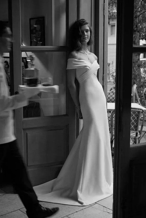 an elegant modern off the shoulder wedding dress with a draped bodice and a plain skirt with a train is pure chic
