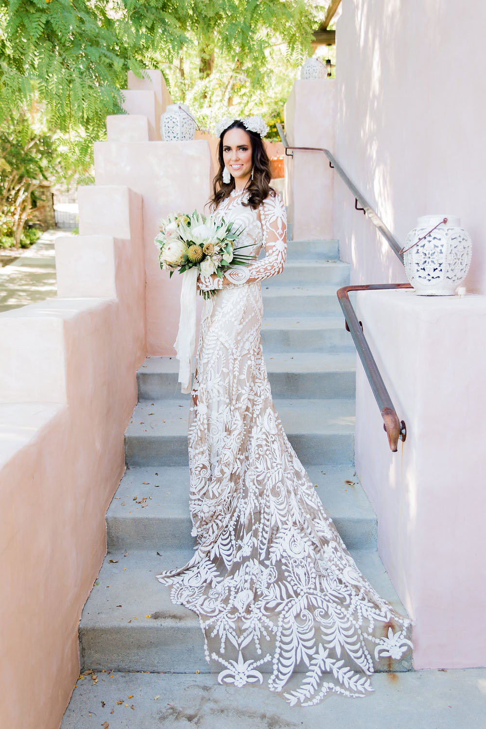 The bride was wearing a boho wedding gown with large lace appliques and illusion parts and completed the look with statement earrings and a crown