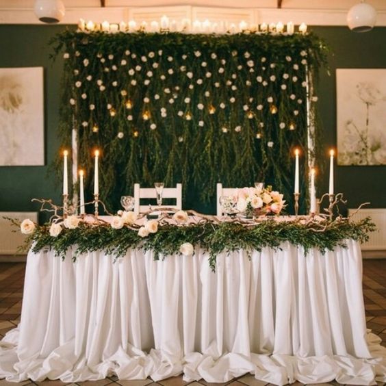 lush greenery with white blooms and candles on top for a woodland-inspired wedding