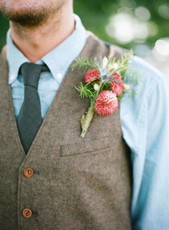 a chambray shirt, a grey tie and a brown waistcoat with a coral bloom boutonniere