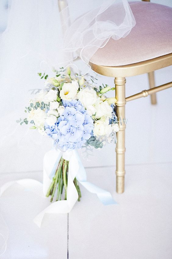a beautiful bouquet of white blooms and blue hydrangeas, eucalyptus and with blue ribbons