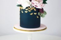 08 a matte navy wedding cake topped with lush blooms and greenery