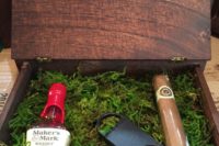 10 a stained wooden box with moss, a bottle of alcohol, a cigar, a cigar cutter for a woodland-themed wedding