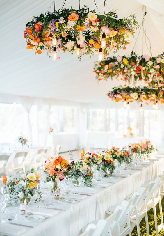 bold floral chandeliers over the tables and matching blooms on them