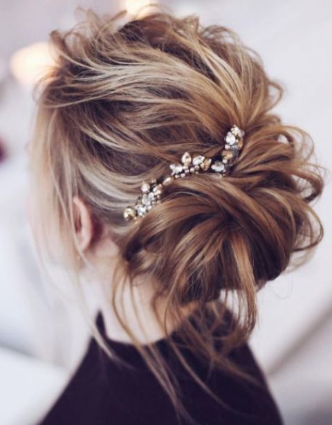 a messy updo with a rhinestone hairpiece and some locks down looks effortlessly chic