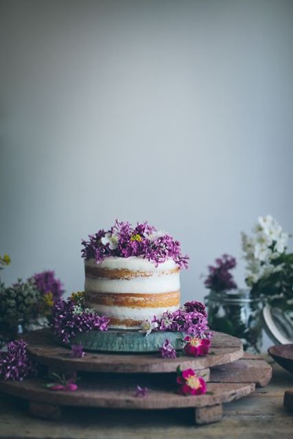 a naked cake topped with lilac and some white blooms for a bold spring look