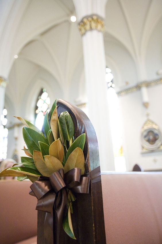 a magnolia leaves arrangement with a brown ribbon bow for the aisle decor