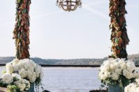 19 a small chandelier suspended from the center of the alfresco ceremony arch, which is made of magnolia-leaf garlands