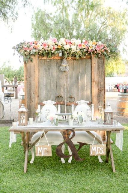 an old wooden door backdrop with a glam chandelier and lush blooms and foliage on top
