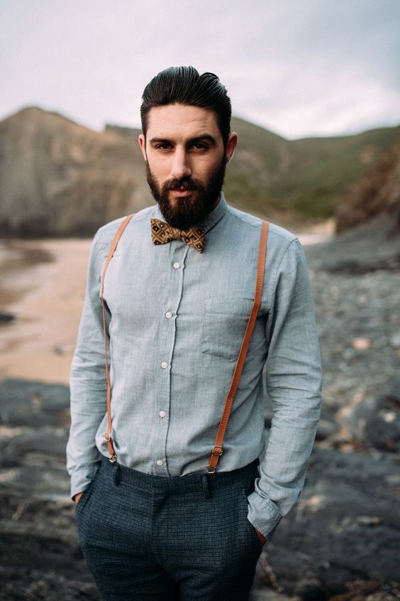 dark grey tweed pants, a light grey shirt, a brown printed bow tie and amber leather suspenders for a vintage feel
