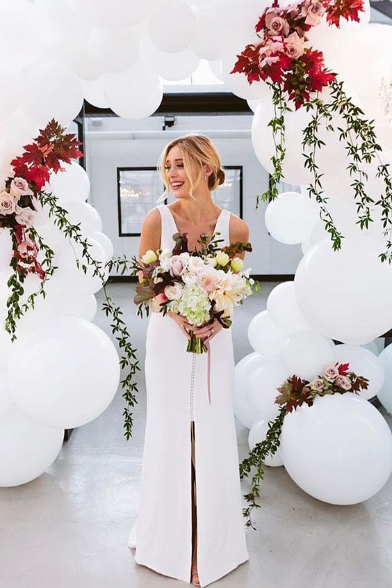 a gorgeous wedding arch of white balloons and bold blooms for a modern ceremony