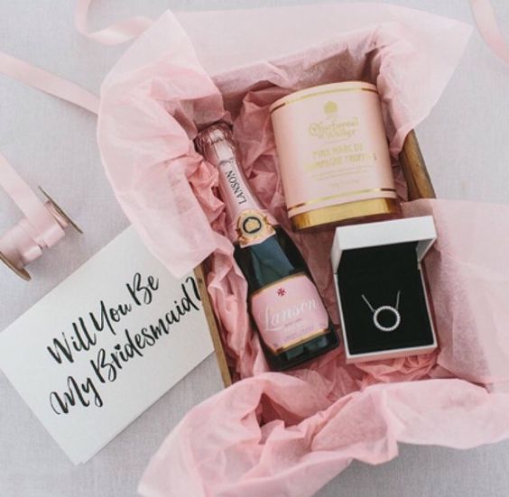 a chic and glam bridesmaids' kit with a necklace, a candle and a bottle of pink champagne