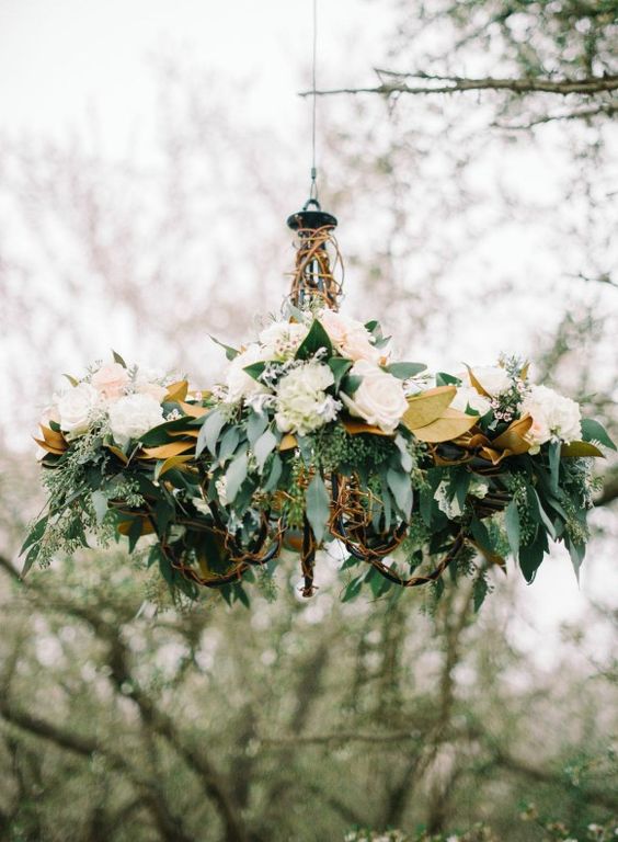 a stylish rustic chandelier with magnolia leaves, neutral blooms and eucalyptus