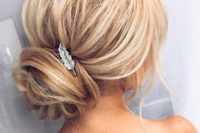 22 a voluminous updo with a wrapped low bun and a small feather hairpiece for an elegant touch