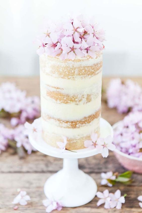 a tall and small wedding cake topped with pink cherry blossom