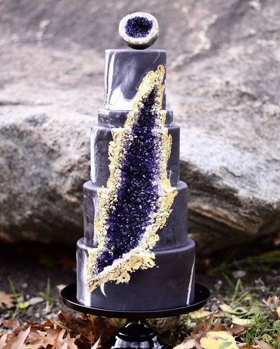 marbleized purple wedding cake with amethyst and gold decor and a piee of geode on top