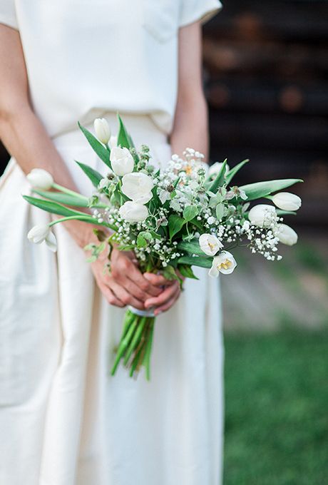 a minimalist bridal bouquet with white tulips, baby's breath, thistles and leaves for a modern bride