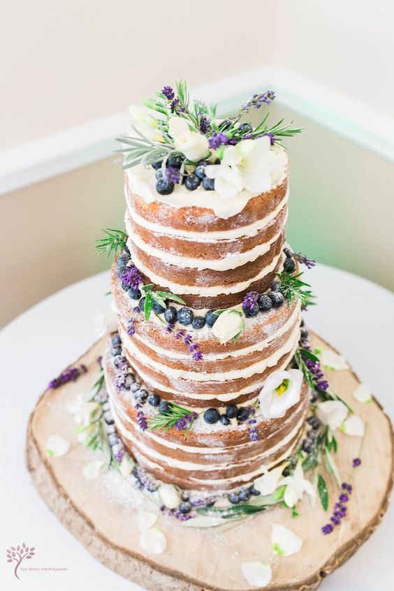 naked spring wedding cake topped with blueberries, lavender and some white blooms