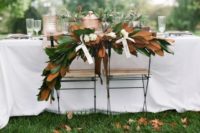 28 the couple’s chairs decorated with magnolia leaves and ribbon bows