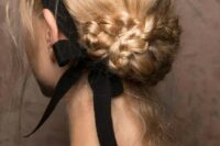 a beautiful braided low updo with a volume on top and a black ribbon bow for a super elegant and girlish look