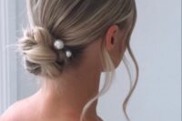 a beautiful woven twisted low bun with pearl hair pins and waves down is a lovely and modern solution for a wedding