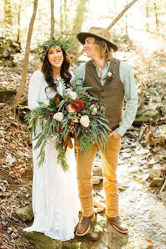 a boho meets rustic groom's look with a green printed shirt, mustard trousers, a brown vest, brown shoes and a tan hat