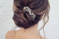a chic French twist updo with a volume on top and locks down with a rhinestone hairpiece