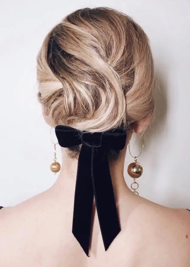 a chic updo made of medium length hair with twists and waves and a black velvet bow is a stylish idea with a glam touch