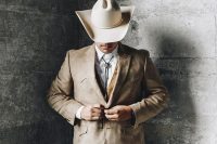 a country groom’s look with a white shirt, black trousers, a tan waistcoat and a blazer, a creamy hat