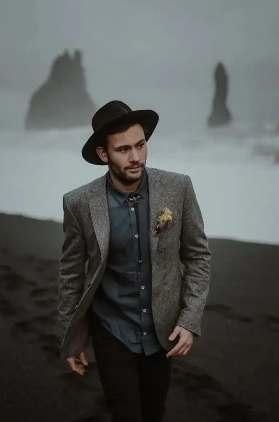 a graphite grey shirt, a grey woolen blazer, a bolo tie, a black hat and black jeans for an adventurous elopement