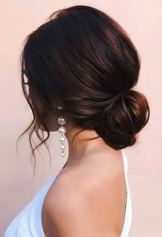 a loose low bun with a volume on top and some wavy locks down is a chic and beautiful idea for a modern wedding