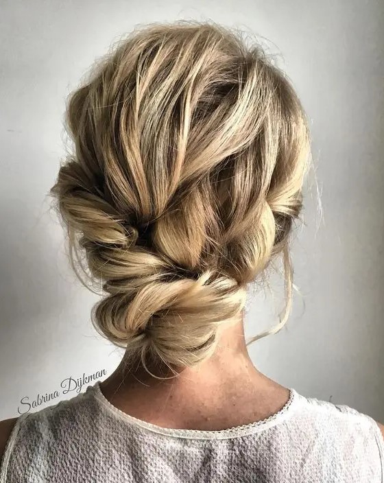 a lovely messy low updo with a twisted top and a twisted lower part for a non-formal wedding