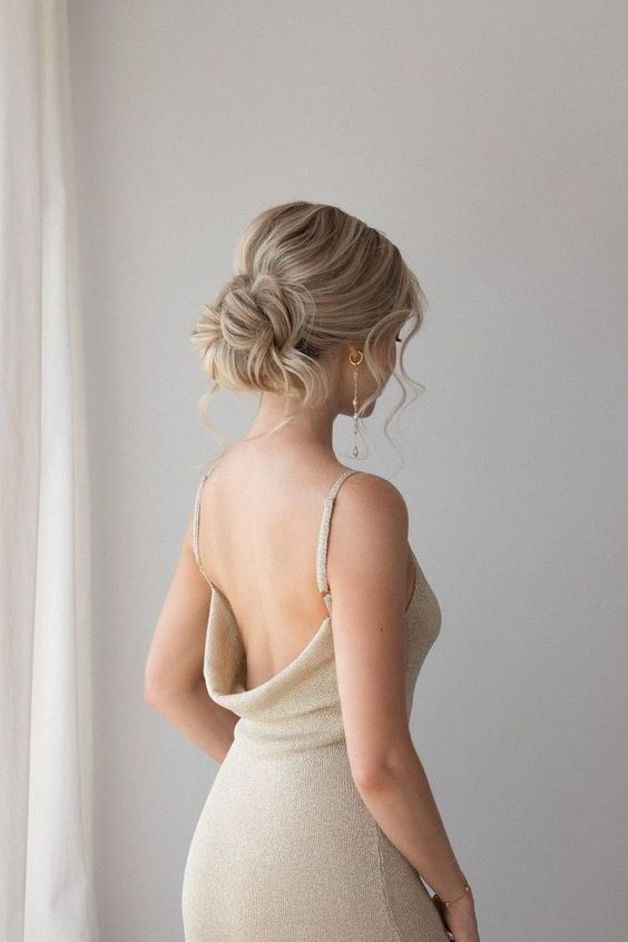 a messy and chic low updo with a bump on top and some waves down is an elegant and beautiful hairstyle
