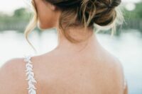 a messy and loose twisted low updo with some waves down is a cool idea for a wedding