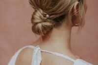 a messy low bun with a bump on top and a pearl hair pin, with some locks down, is a chic and cool hairstyle