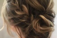 a messy updo with a braid on one side, a messy and voluminous top, some locks down and a twisted bun