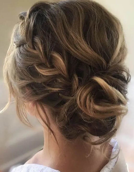 a messy updo with a braid on one side, a messy and voluminous top, some locks down and a twisted bun