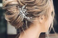 a messy wavy French twist updo with a messy top, a messy twisted chignon and locks down plus a rhinestone hairpiece