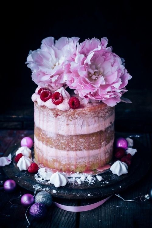 a naked wedding cake with pink drip, fresh raspberries, pink peonies and meringues is an adorable dessert for spring
