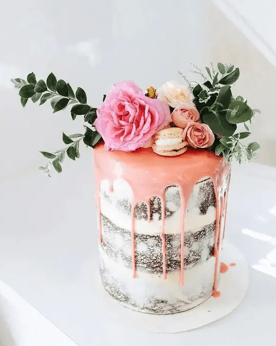 a naked wedding cake with pink drip, vanilla macarons, fresh blooms and foliage is a perfect idea for spring or summer