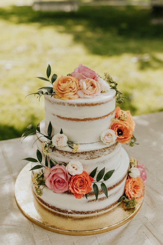 a pretty naked wedding cake decorated with bold blooms and leaves is a cool idea for spring and summer