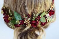 a pretty wedding low bun on medium length hair accented with burgundy blooms and greenery is a lovely and comfy idea