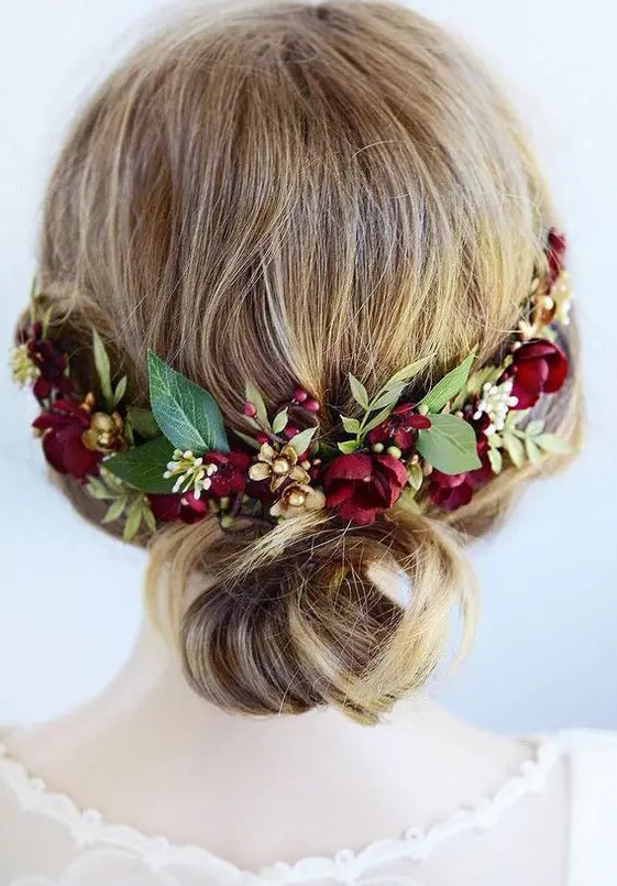 a pretty wedding low bun on medium length hair accented with burgundy blooms and greenery is a lovely and comfy idea