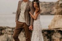 a relaxed groom’s outfit with a neutral t-shirt, rust-colored pants, a grey blazer and a brown hat plus black shoes is cool for a boho wedding