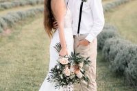 a relaxed rustic groom’s look with a white shirt, tan pants, black suspenders, a neutra hat and brown loafers