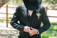 a rustic groom’s look with navy jeans, a black waistcoat and a blazer, a black hat, a white shirt and a pink tie